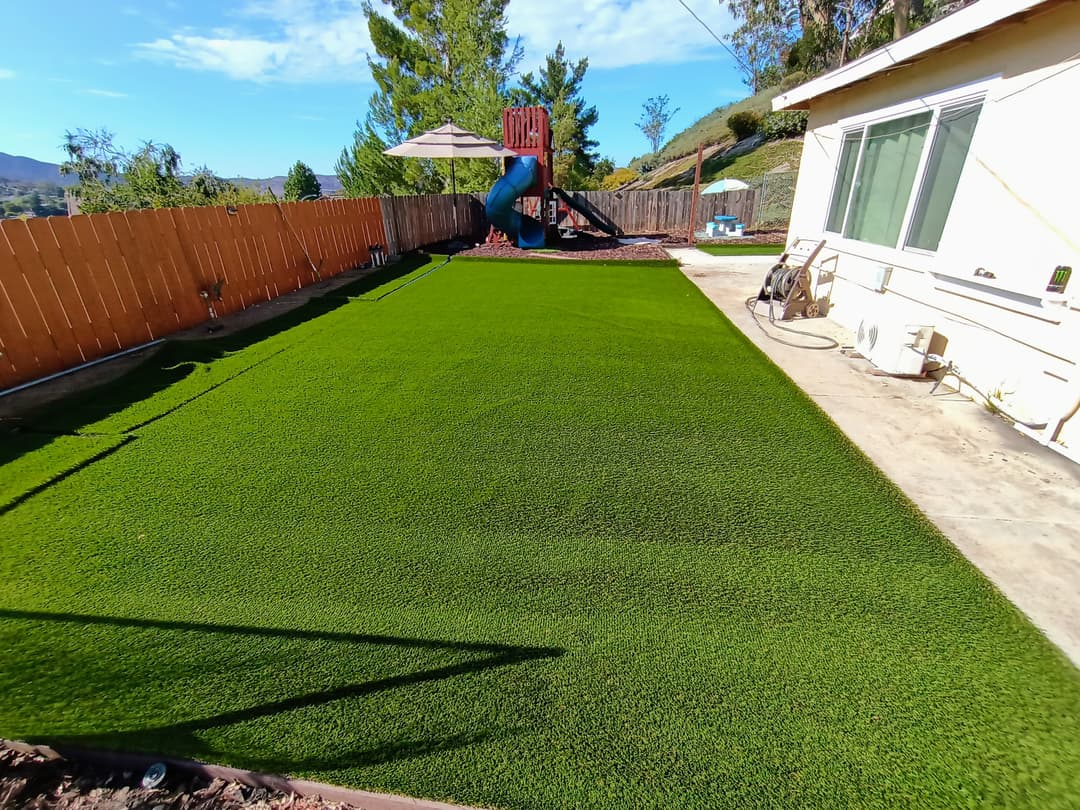 backyard with newly installed artificial turf and playground set