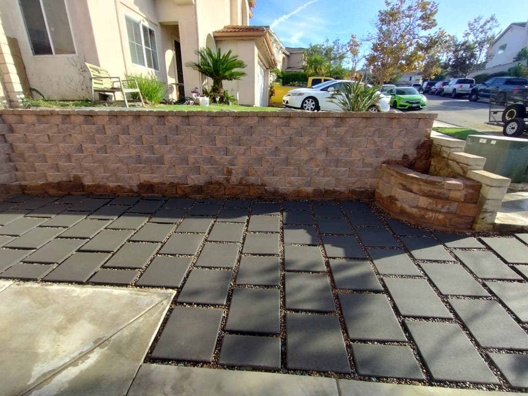 front yard with dark pavers and decorative retaining wall